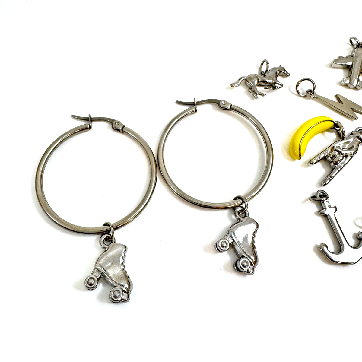 FOXLARK The Everyday Charm Collector Hoop Earrings featuring round tube stainless steel hoops with lucky charm charms on a white background.