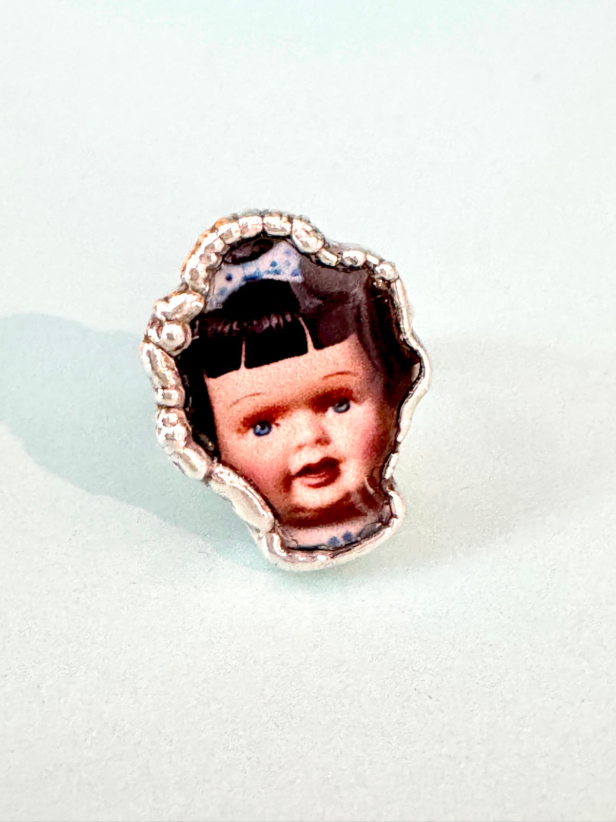 Blue bow doll head statement ring in fine silver, size 9, from FOXLARK's Weirdlings Collection, featuring intricate design details.
