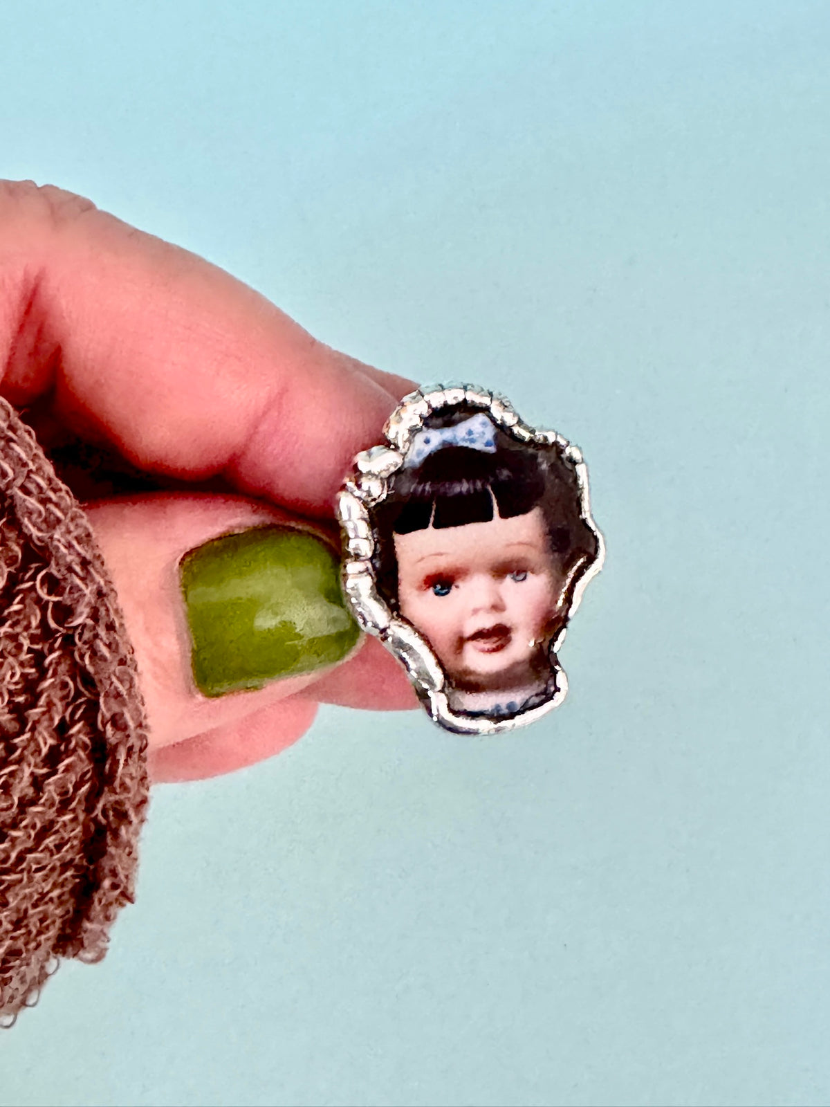 Blue bow doll head statement ring in fine silver, size 9, from FOXLARK's Weirdlings Collection, detailed silver jewelry image.