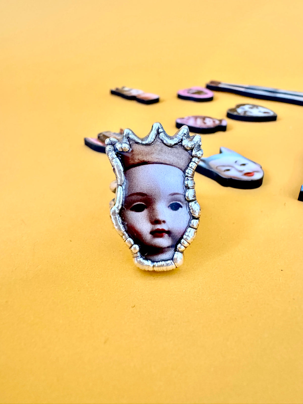 Close-up of FOXLARK Doll Head Statement Ring in fine silver, size 8 from The Weirdlings Collection with detailed doll head design.