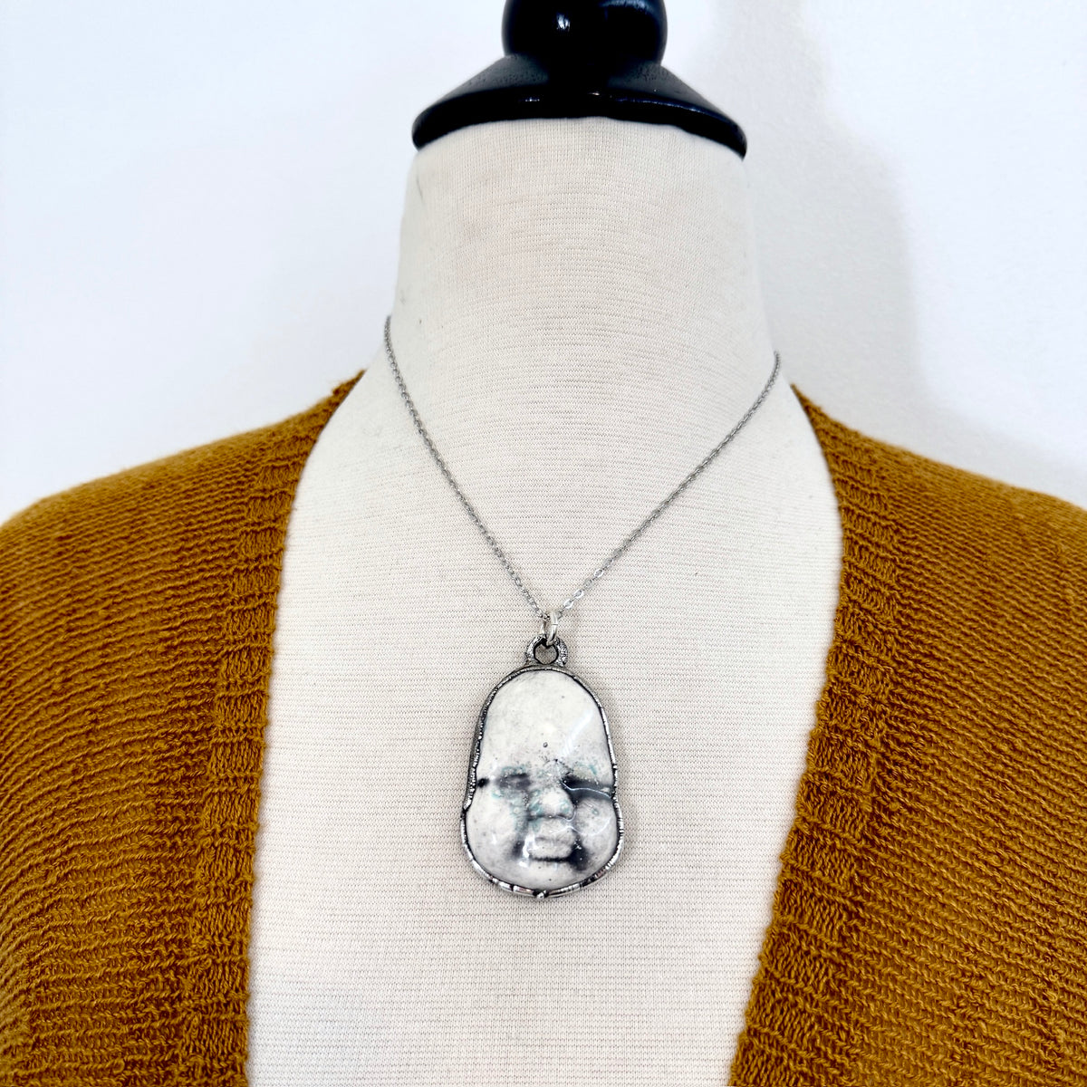 Ceramic baby doll face necklace by FOXLARK from the Foxlark Collection, featuring a fine silver chain and unique doll face pendant.
