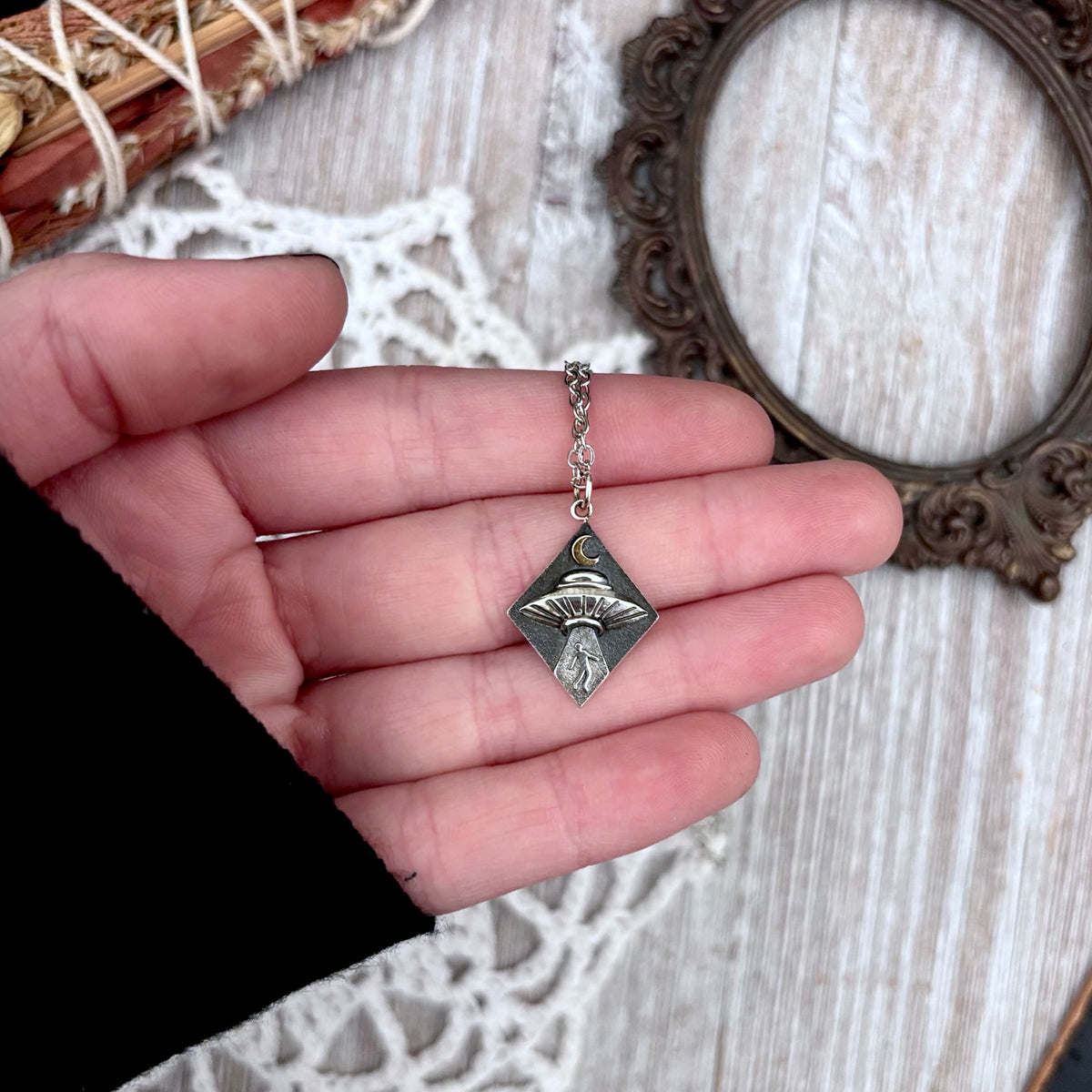 Sterling silver UFO abduction necklace pendant from FOXLARK Tiny Talisman Collection featuring a small, detailed alien spacecraft design.