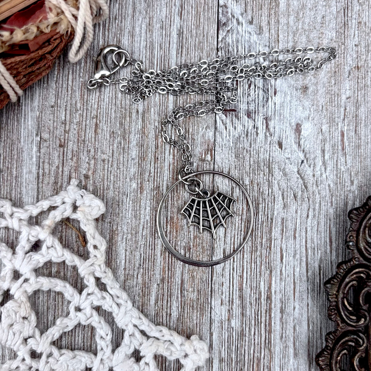 Tiny sterling silver spider web talisman necklace from FOXLARK's Talisman Collection, featuring intricate web design.