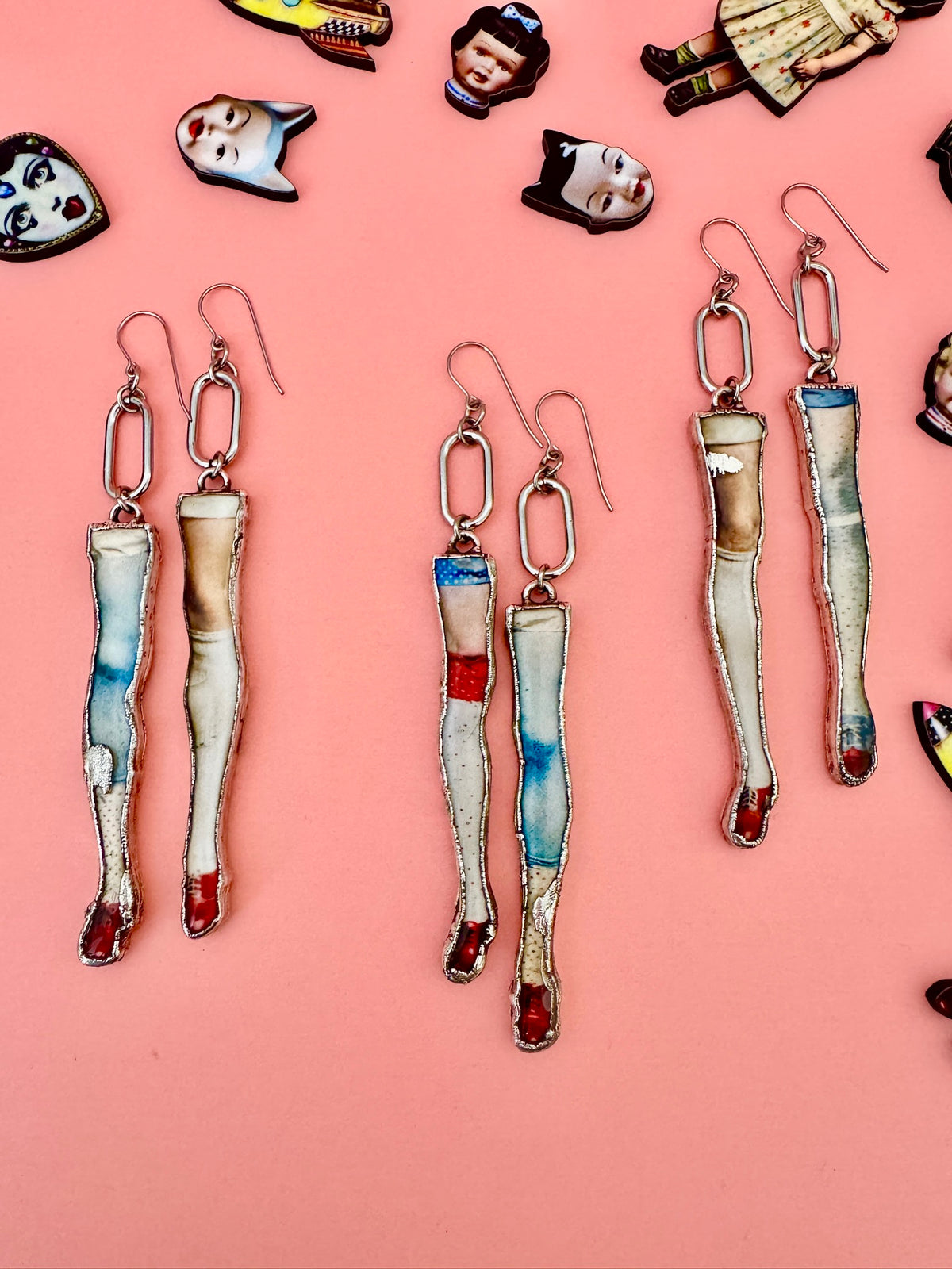 Long mismatched silver doll leg earrings with dangling design from FOXLARK's The Weirdlings Collection, statement jewelry for bold style.