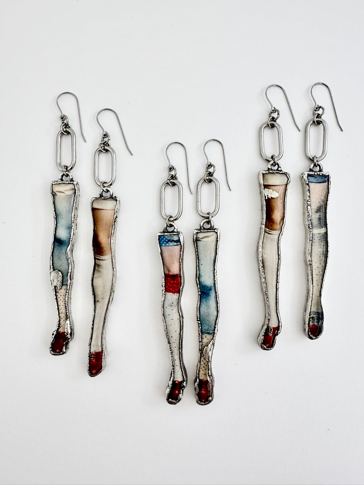 Silver mismatched doll leg earrings with long dangle design from FOXLARK's Weirdlings Collection, statement silver earrings.