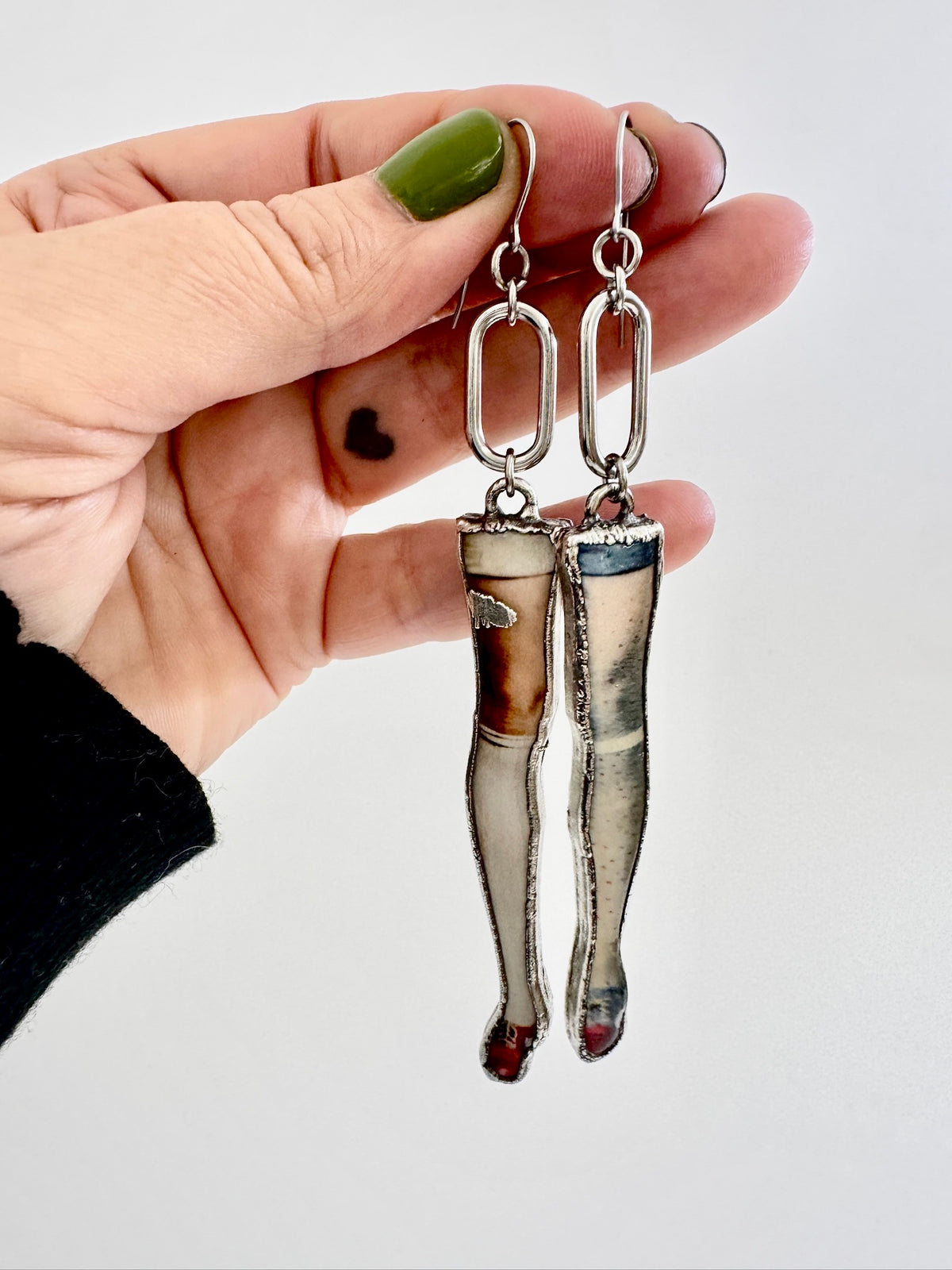Long silver mismatched doll leg earrings with dangling design, from FOXLARK's The Weirdlings Collection, statement jewelry.