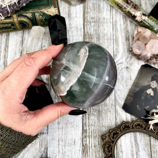 Large green fluorite crystal ball from FoxlarkCrystals, smooth polished stone with vibrant green hues and natural crystal patterns.
